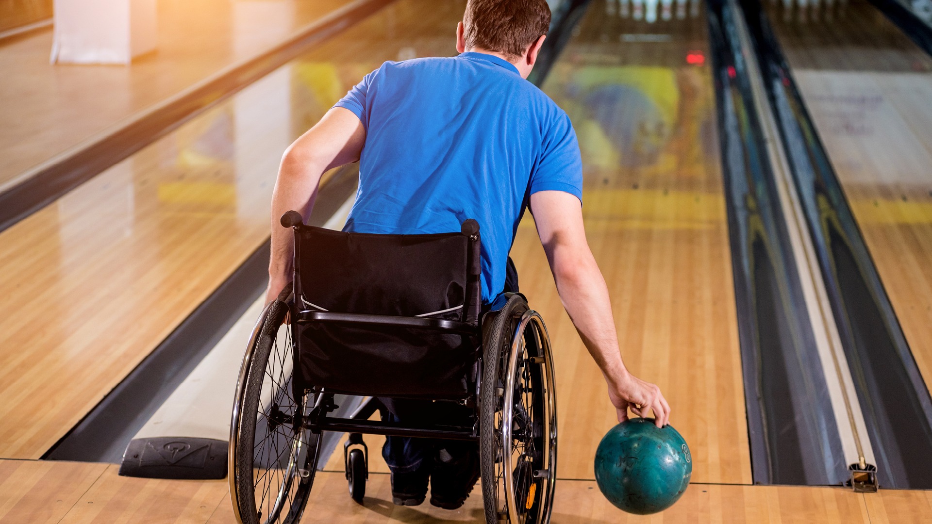 Man in blue shirt bowling from wheelchair