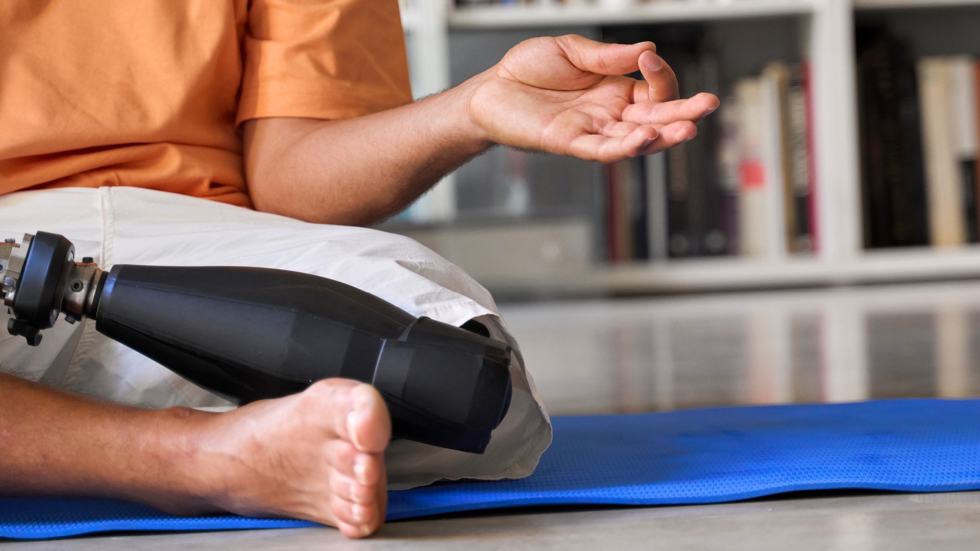 Male on yoga mat with prosthetic leg performing a lotus position