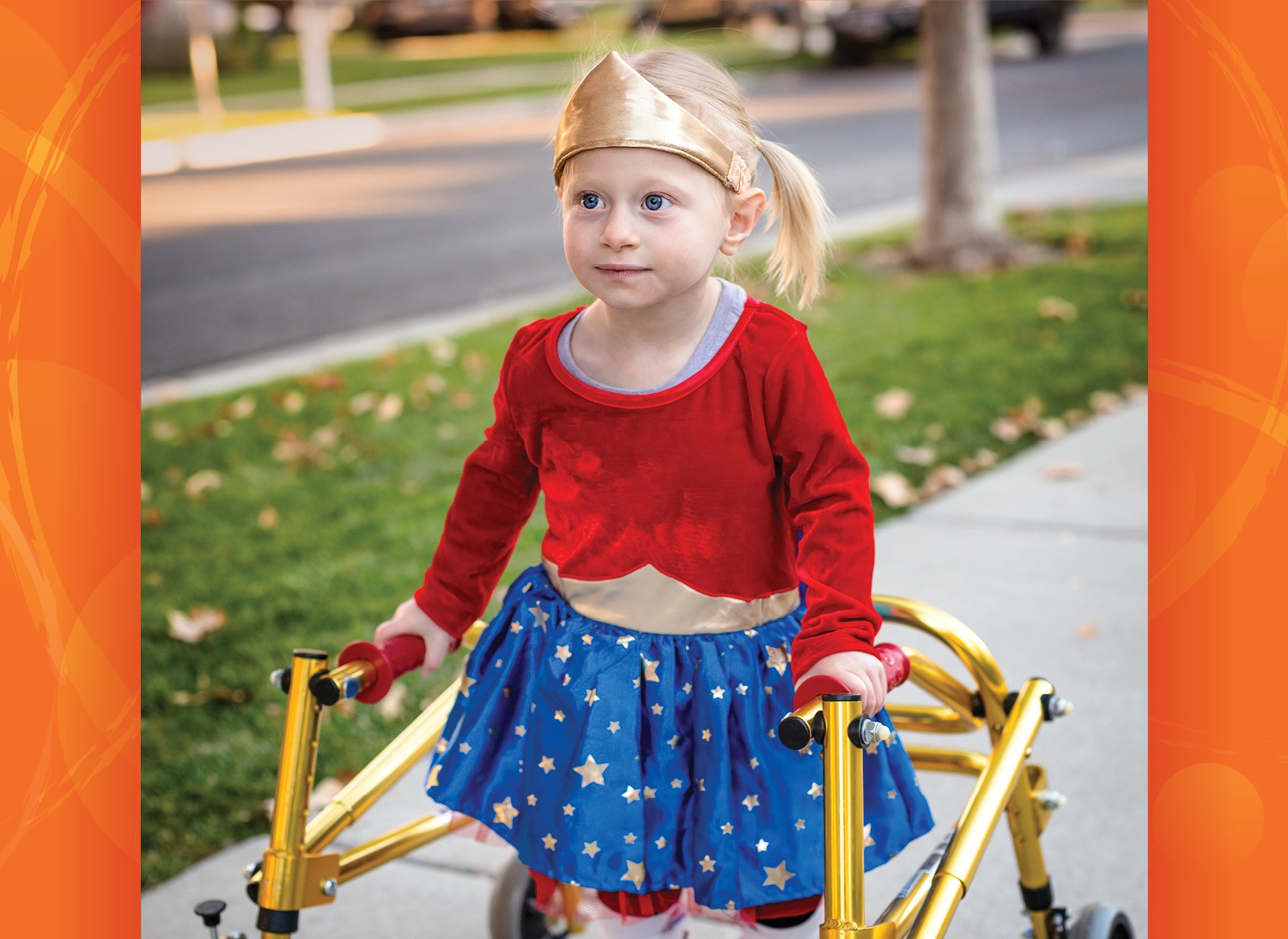 young girl with blonde hair wearing red, blue and gold Halloween costume similar to Wonder Woman and using a walker